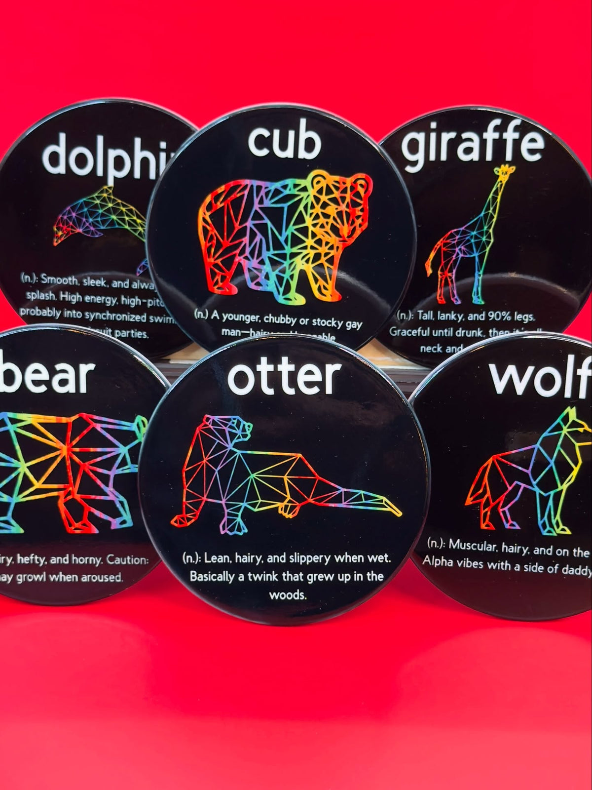 Six rainbow gay animal archetype ceramic coasters on a red background
